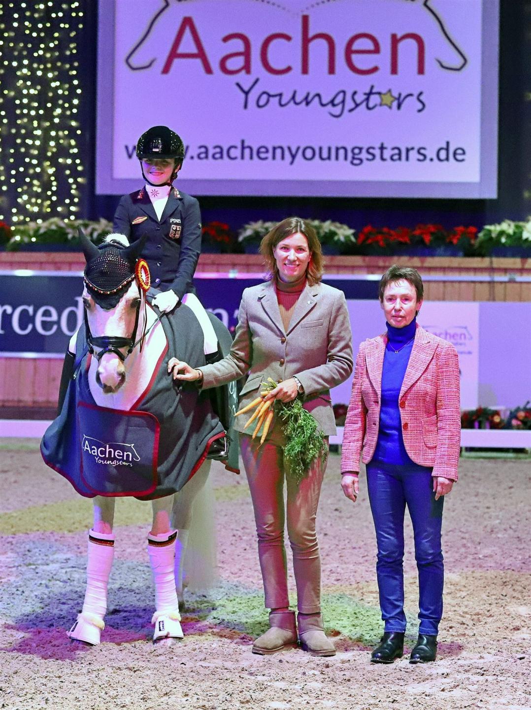 Der glücklichen Siegerin gratulieren Stefanie Peters, Aufsichtsratsmitglied des ALRV, und Ponydressur-Bundestrainerin Cornelia Endres. 